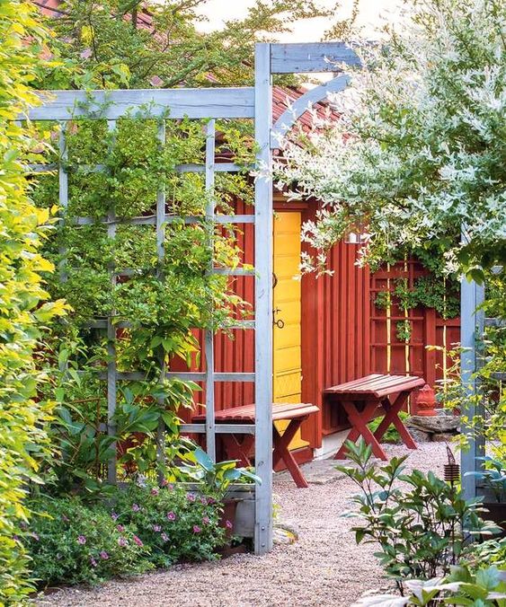 a blue trellis fence covered with various green vines, surrounded with blooms and trees, is a lovely way to divide spaces and get a more lush garden without sacrificing the space