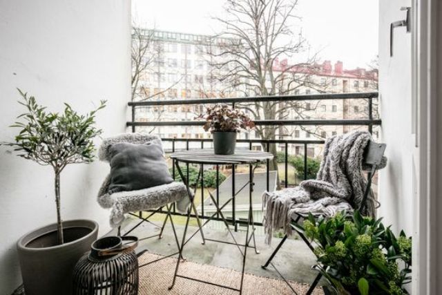 a small balcony with folding furniture, potted greenery and candles for having meals