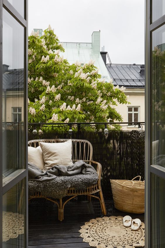 a rustic balcony with a wicker seat, a jute rug and a straw bag looks very cozy and welcoming