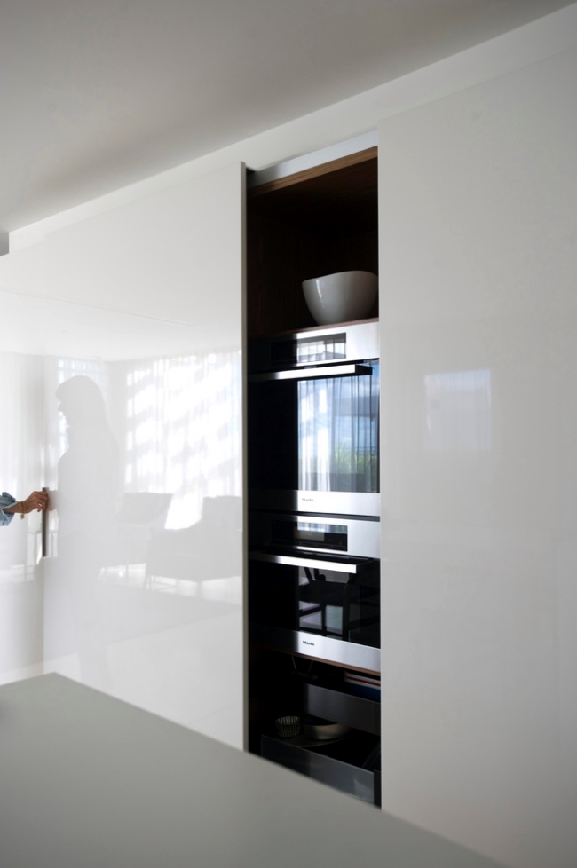 an oversized glossy sleek cabinet with a sliding door that hides all the kitchen stuff you may need and keeps the space neat