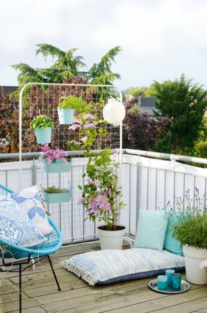 a balcony with some colorful furniture, accessories and pillows, potted plants, a screen with planters and some vines climbing up