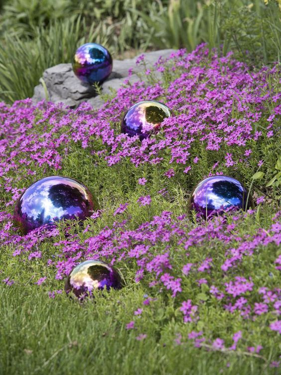 a beautiful purple flower bed with blue and purple glossy garden balls that make it outstanding and very cool