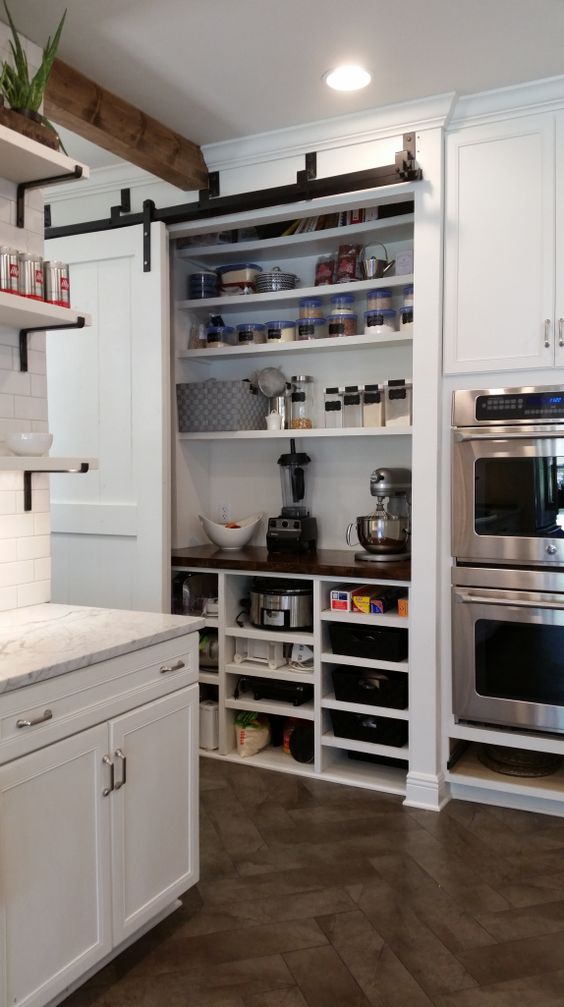 a built-in pantry with a sliding door holds various appliances, spices, food, jars and tableware is a very smart solution to hide everything