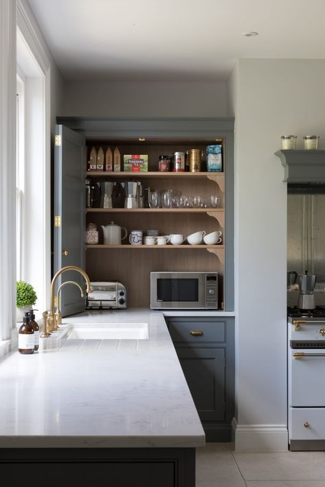 a cabinet with appliances, jars, mugs, cups and other stuff is a little coffee station that can be hidden with a folding door