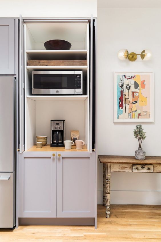 a cabinet with shelves that hides several appliances and creates a mini tea and coffee station you may use