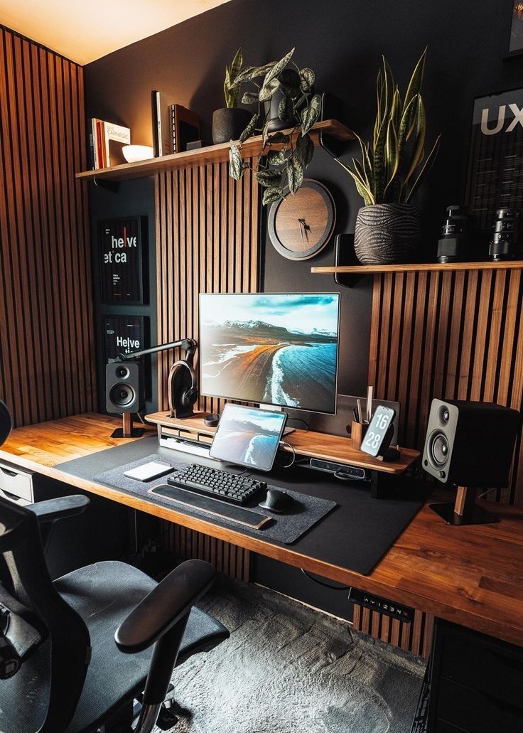 a chic modern home office with a black accent wall and planks, a chair, a PC, shelves with potted plants, books and a clock