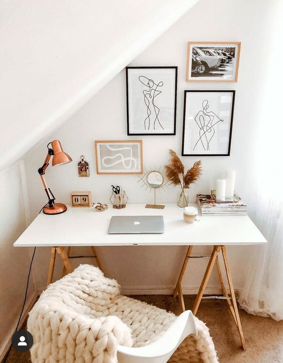 a chic Scandinavian workspace with a trestle desk, a gallery wall, a lamp, candles and some decor