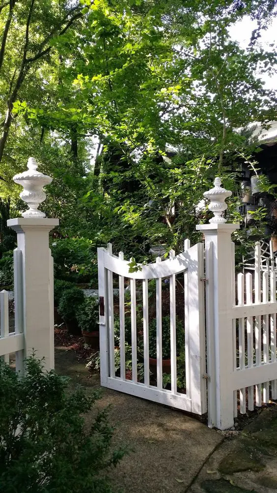 a classic white fence and a small curved gate are a cool idea if you love classics and even vintage and want that feel for your space