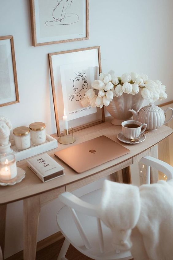 a clean and minimal neutral workspace with a small desk, a chair, a gallery wall, blooms and chic candles and decor