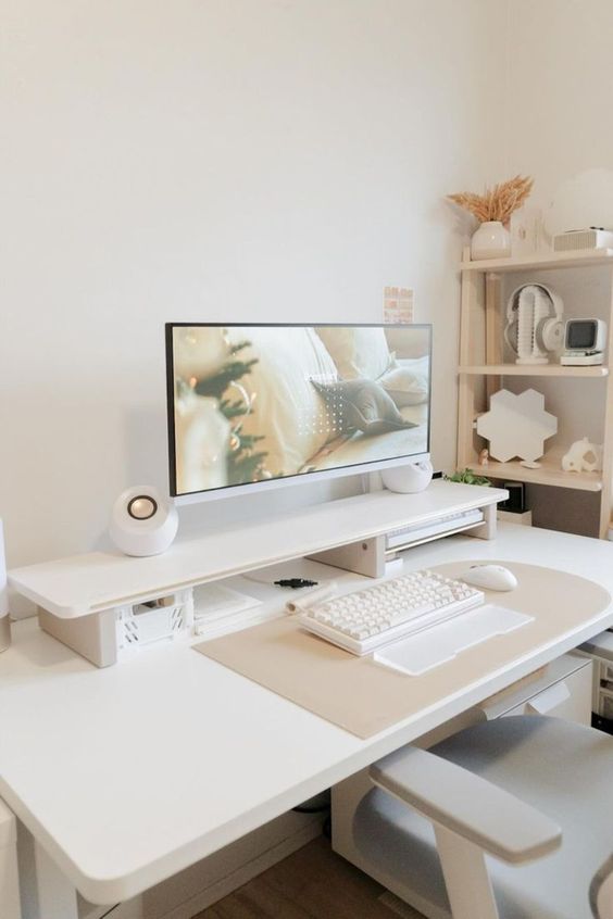 a clean and minimal workspace with a white desk, a chair, a shelving unit with cool decor, a PC and speakers