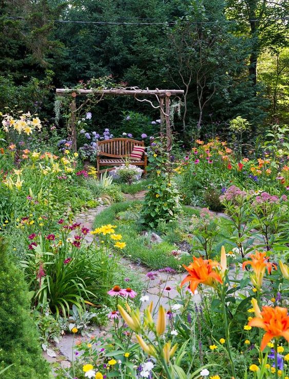 a colorful secret garden done with bold and bright blooms and greenery, with an arch over the bench is a lovely space to spend time in