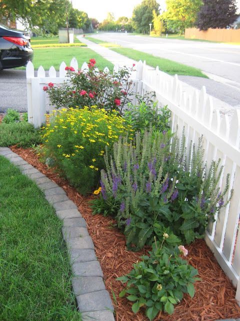 a corner garden by the fence with greenery and bright flowers is a cool idea to add curb appeal to your space