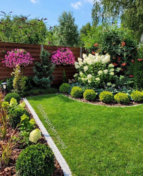 a corner garden with a green lawn, some trees, bright blooms and elegant topiaries is a great and chic space