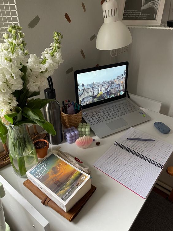 a cozy little working space with a laptop, some books, blooms, candles and a lamp is amazing