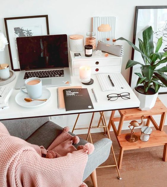 a cozy modern workspace with a desk and a chair, a ladder as a shelf, a PC and some devices, candles and various decor