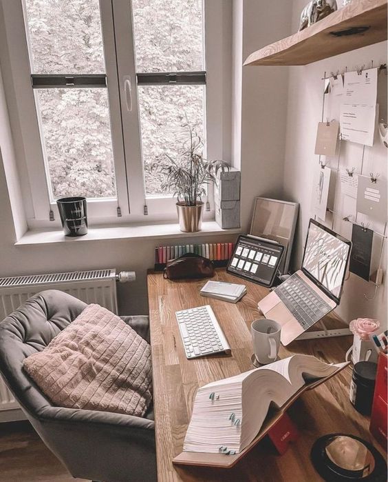 a cozy workspace with a desk and devices, some decor, a shelf,a  grid as a memo board and a chair with a pillow