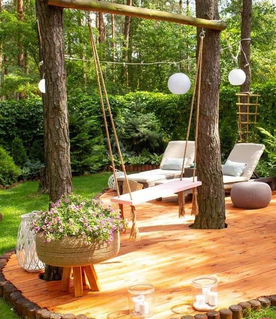 a deck with loungers, a pink swing, some blooms, lights and a pouf is a cool and catchy idea