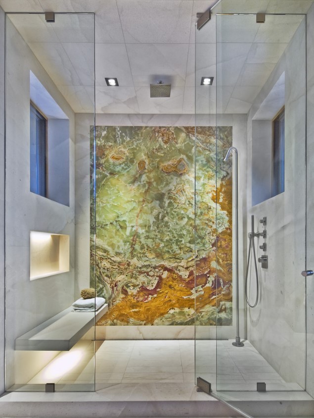 a fantastic neutral shower clad with white marble tiles and a gorgeous stone wall for an accent, a bench and illuminated niches