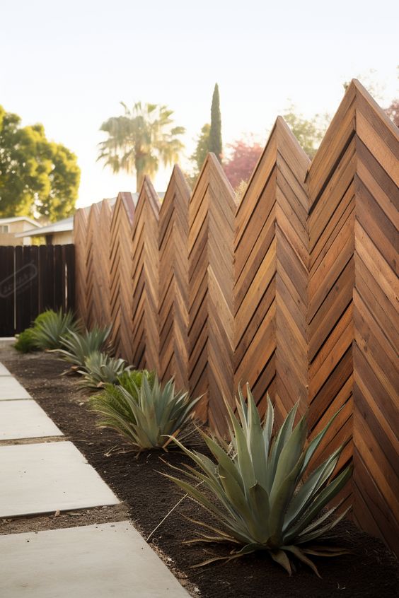 a fantastic stained chevron wooden fence lined up with a garden bed with agaves is a lovely idea for a modern outdoor space