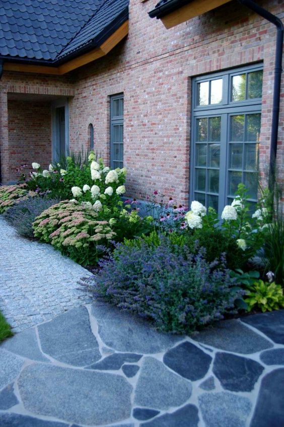 A large flower bed along the house with blooms and lavender is a cool and catchy addition to the front yard.