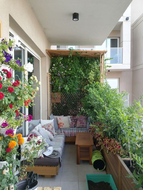 a garden-style balcony with a trellis and greenery, potted plants and blooms, a corner sofa and pillows is amazing