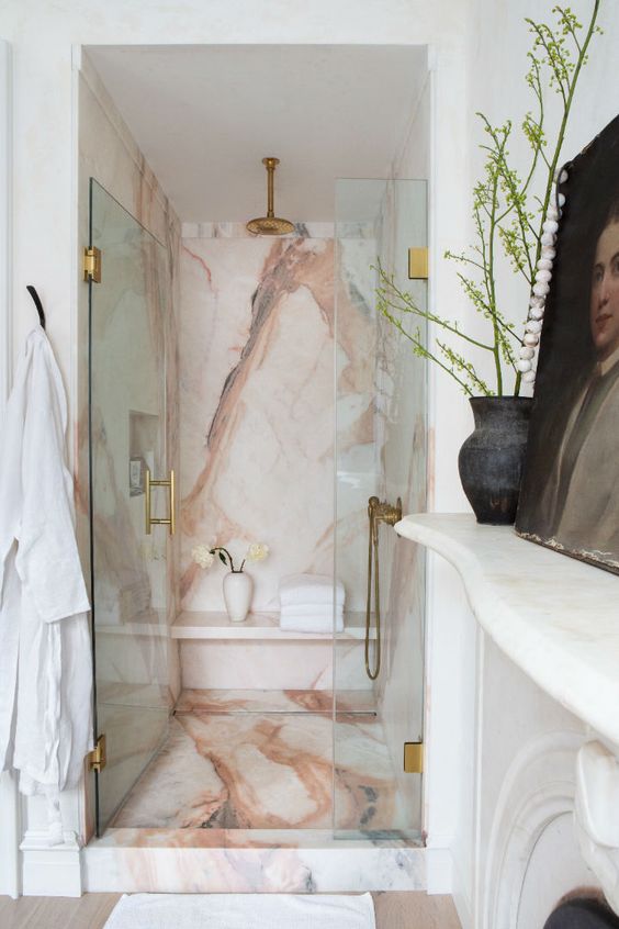 a gorgeous pink marble shower space wiht glass doors and elegant copper fixtures is a lovely idea that looks super refined