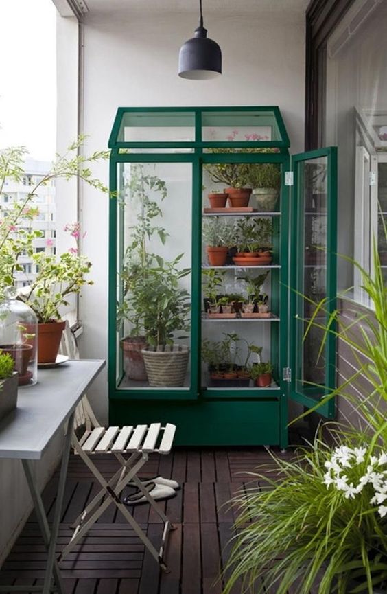 a green greenhouse with lots of potted plants and more plants around it for a spring look