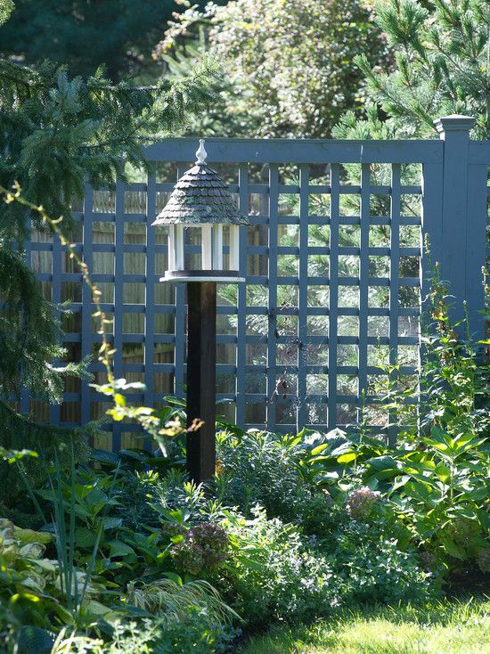 a grey metal grid fence lined up with greenery is a cool idea of a fence that looks lightweight and makes the garden more private without looking bulky