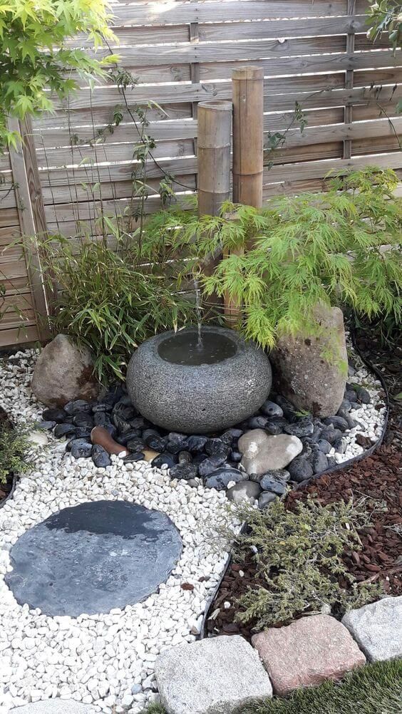 a Japanese corner garden with pebbles, a bamboo fountain, grasses and greenery is a cool and lovely idea