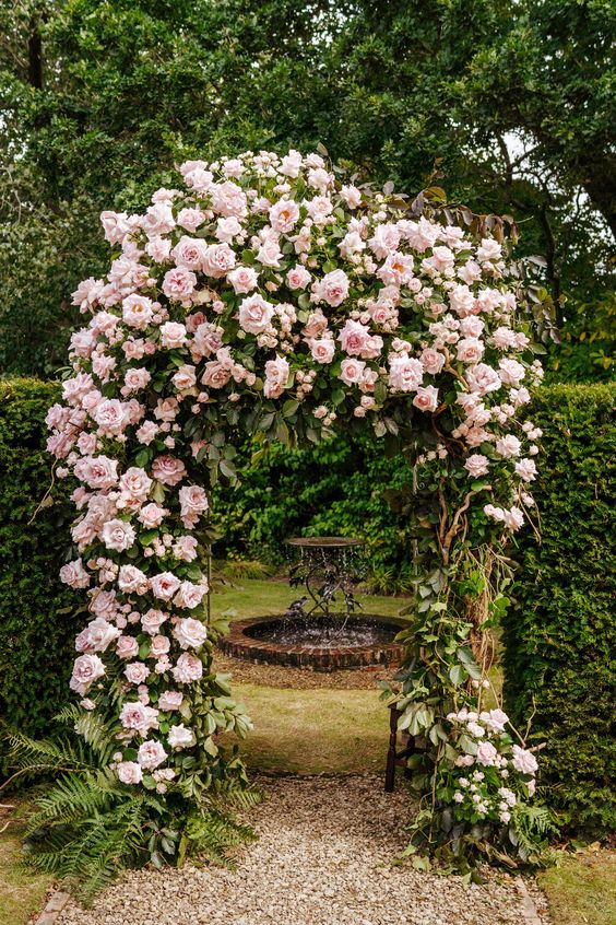 a jaw-dropping arch covered with pink roses as an entrance to a little space with a fountain is a stunning idea for a any garden