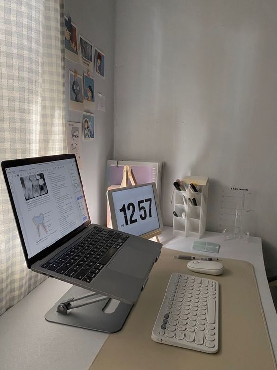 a laconic work and study space with a laptop on a stand, some organizers, a gallery wall of photos