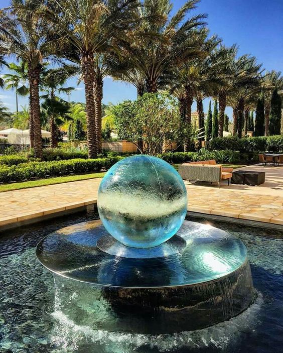 a large pool with a raised metal bowl and a glass sphere on top is a fab modern water feature for any outdoor space