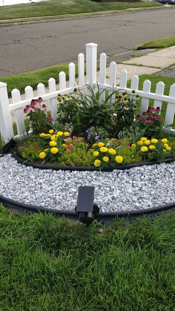 a little corner garden with bright flowers and pebbles plus a spotlight is a cool idea to style a corner