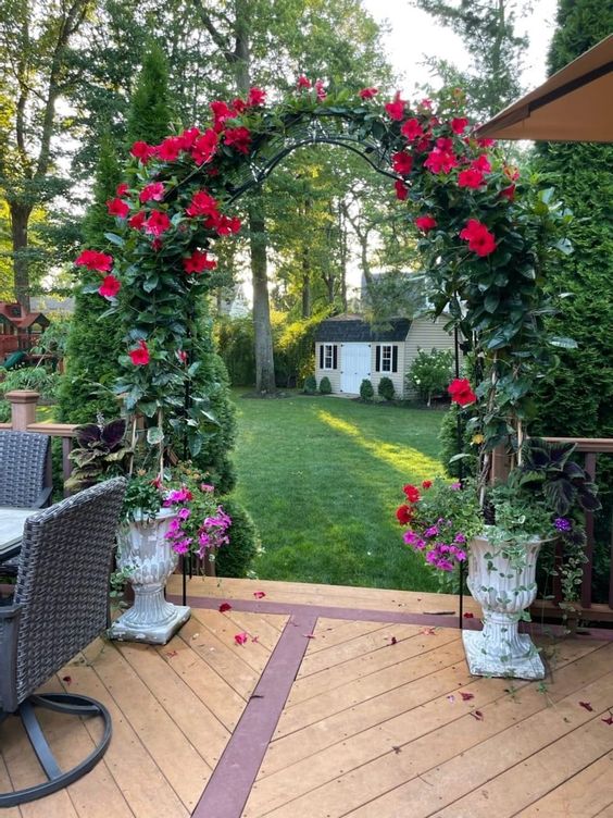 a lovely metal trellis arch done with greenery and red blooms is a gorgeous garden decoration or entrance to another space