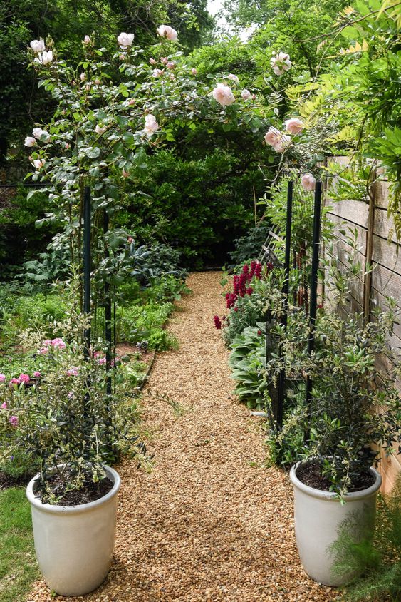 a metal arch covered with blush roses and greenery is a gorgeous decoration for outdoors, or an entrance to some space