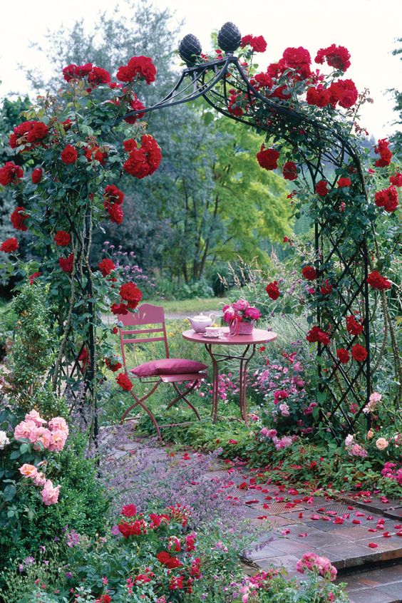 a metal beautifully shaped trellis arch covered with red roses is a gorgeous idea for a fairy-tale or secret garden space