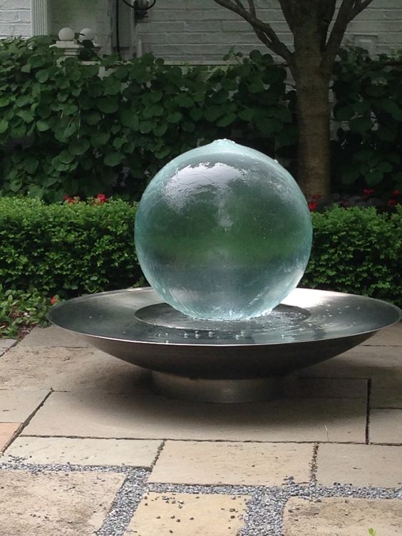 a metal bowl with a gazing ball fountain is a unique decoration for a modern outdoor space