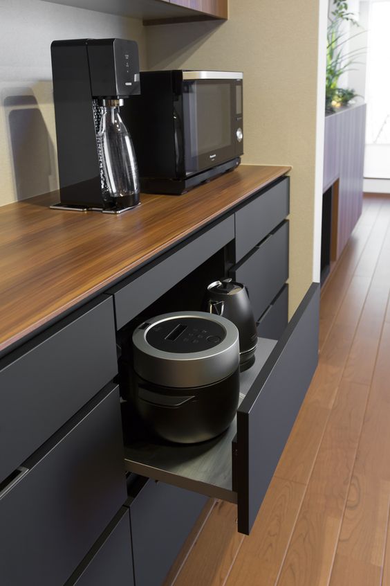 a minimalist black kitchen with an oversized drawer with black appliances keep the kitchen neater and decluttered