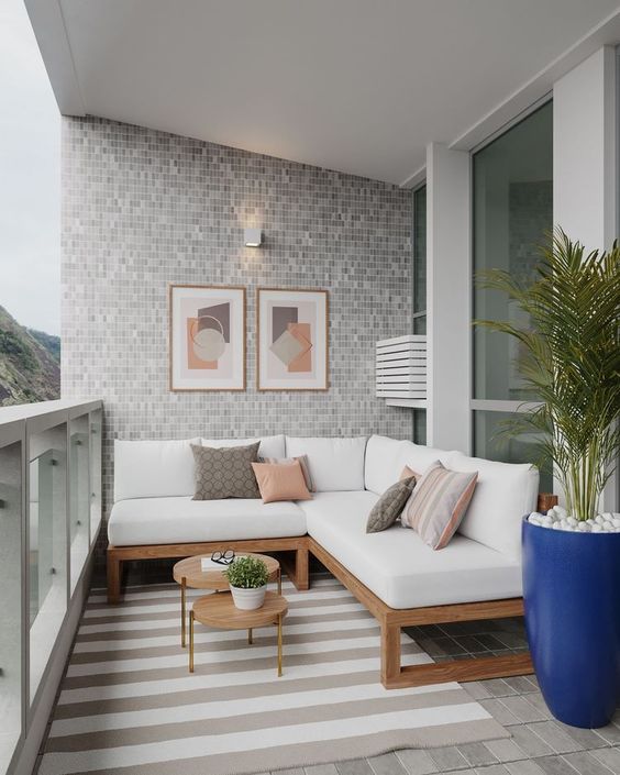 a modern furniture with a white sectional, a striped rug, a potted plant and some artwork