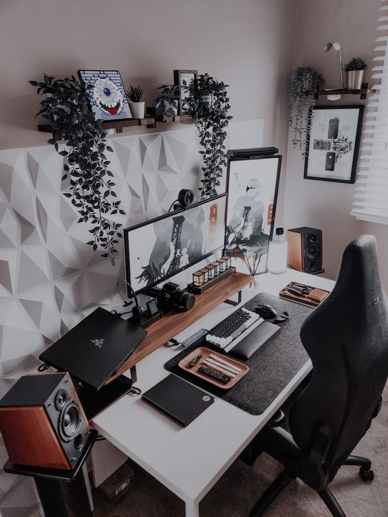 a modern and laconic workspace with some shelves, a desk, greenery and plants, artwork and devices and a PC