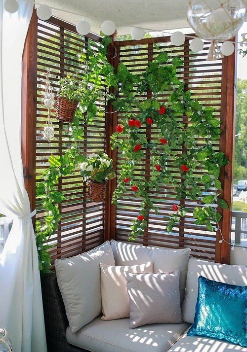 a modern balcony with a sofa with pillows, a trellis with vines and blooms, planters attached is a cool solution