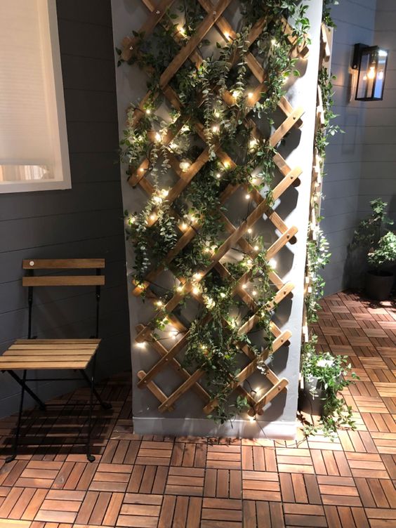 a modern balcony with a trellis with greenery and lights to make the balcony look fresher and cooler