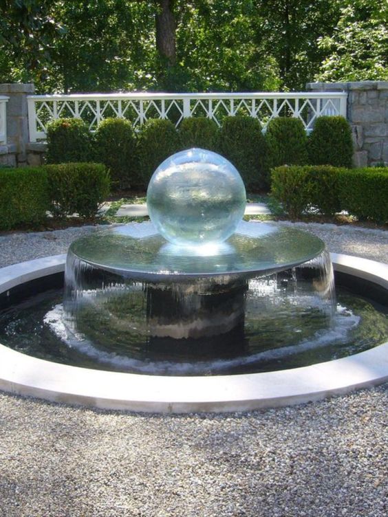 a modern fountain with a raised water bowl with a glass sphere on top for a spectacular touch