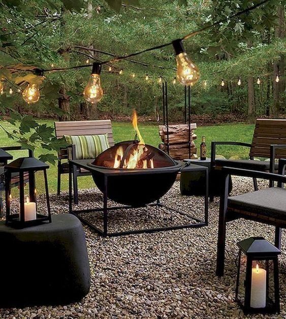 a modern patio with a black fire pit, leather and wooden chairs, lights, pillows and candle lanterns is wow