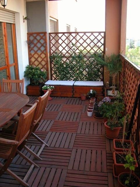 a modern rustic terrace with a stained floor and furniture, potted greenery, a trellis with vines and a bench by it