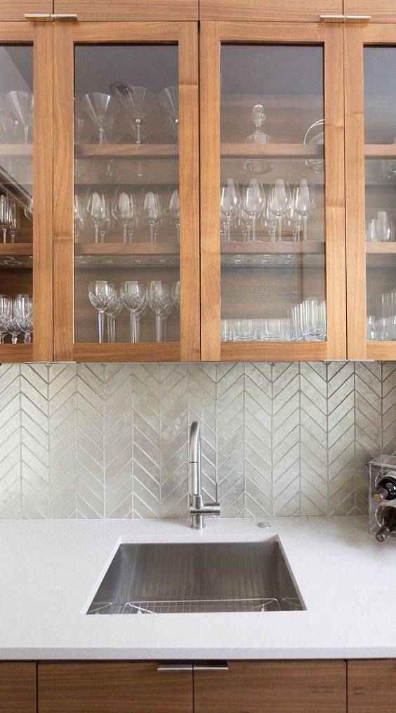 a modern stained kitchen with white countertops and a green chevron backsplash plus stainless steel appliances is amazing