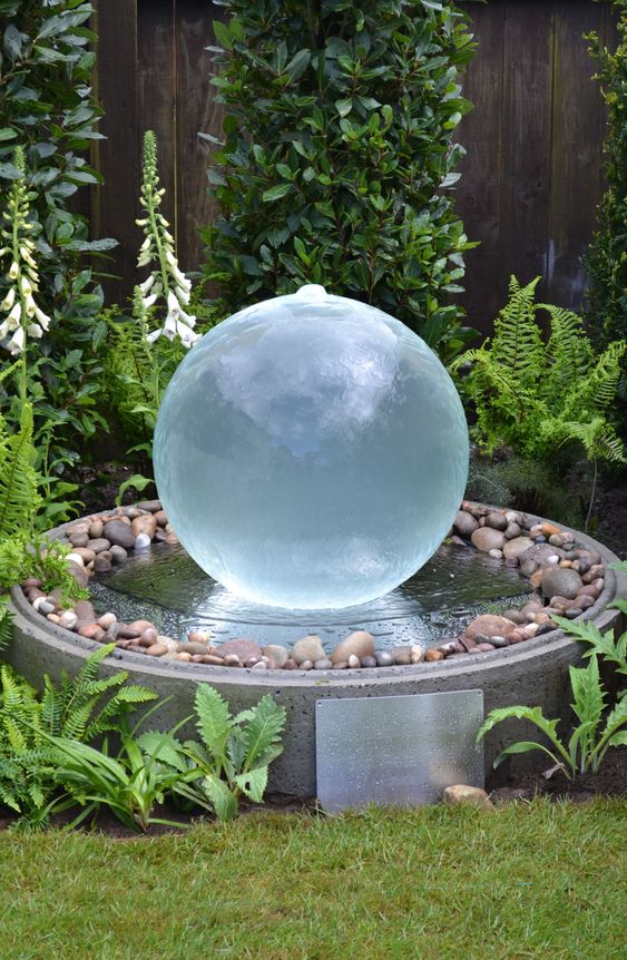 a modern water body of concrete with pebbles and a glass ball fountain in the center is a great decoration for any contemporary garden or even a Zen one