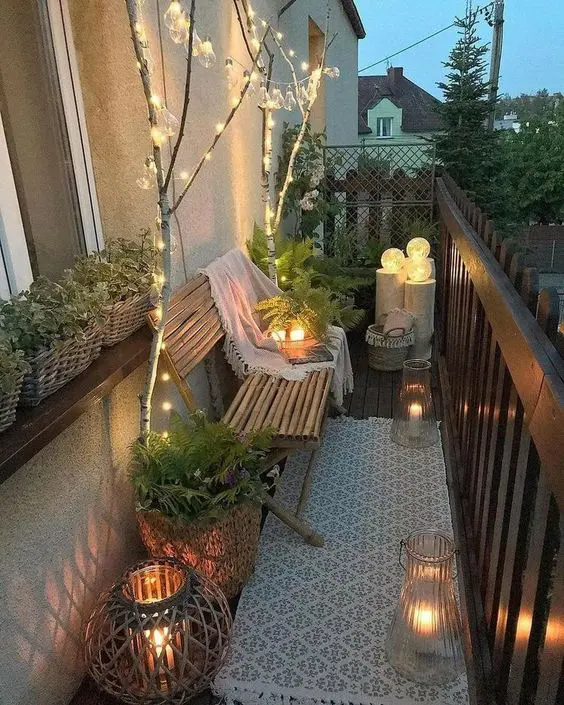 a narrow balcony with a boho rug, a bamboo bench with a blanket, candle lanterns, string lights and lanterns