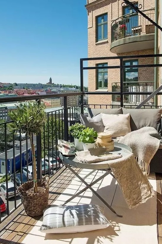 a neutral balcony with metal furniture, neutral textiles, potted greenery and lots of pillows is very welcoming