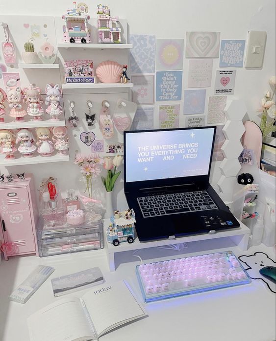 a pastel gaming space with a laptop on a stand, a blush keyboard, shelves with dolls and decor, a gallery wall with various stuff